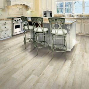 elegant light brown wood floor in the kitchen with an island table and three high top chairs